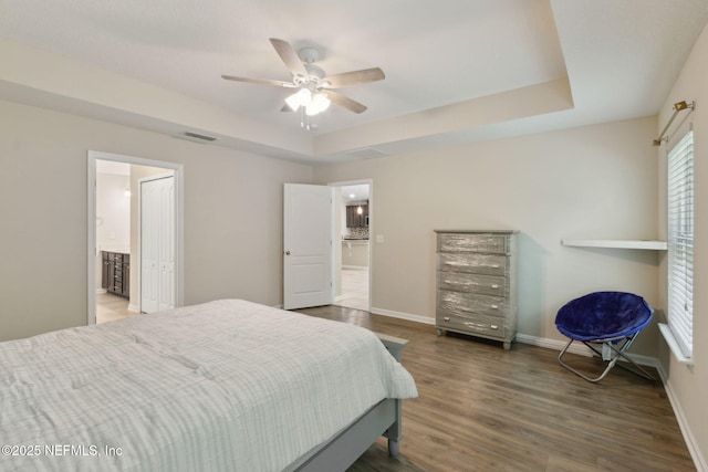 79 Boulder Rock Way, Saint Augustine, FL 32092 - bedroom featuring wood finished floors, a tray ceiling, baseboards, and connected bathroom