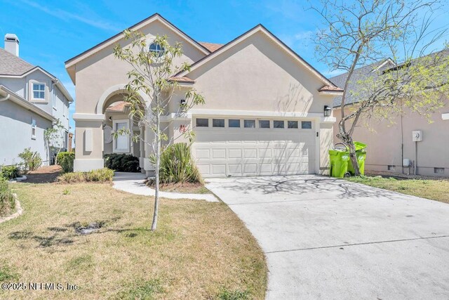 95332 Village Dr, Fernandina Beach, FL 32034 - view of front of home with stucco siding, a garage, concrete driveway, and a front yard
