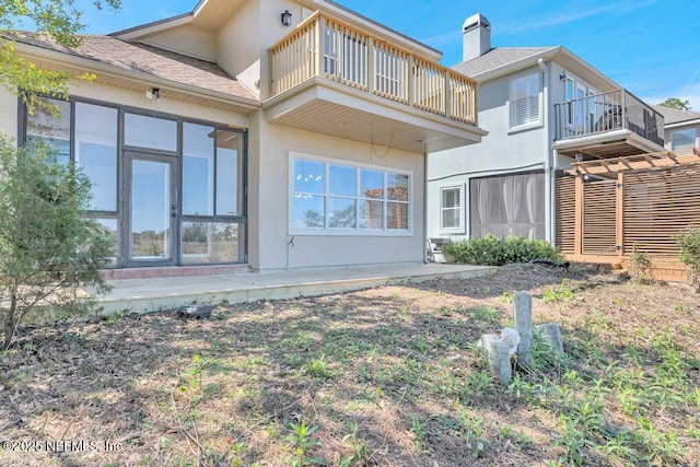 95332 Village Dr, Fernandina Beach, FL 32034 - back of house featuring a balcony, a chimney, and stucco siding