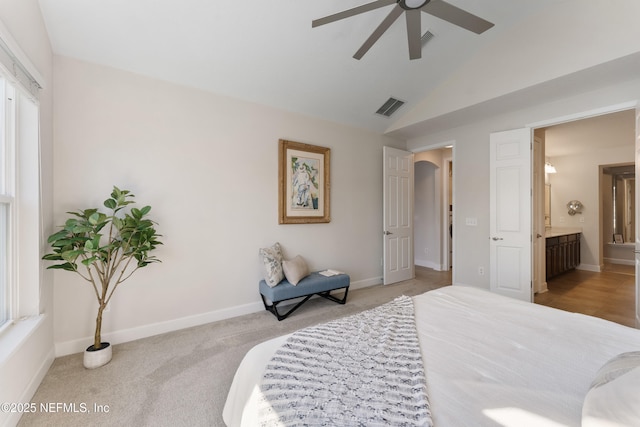 bedroom featuring lofted ceiling, baseboards, carpet floors, arched walkways, and visible vents