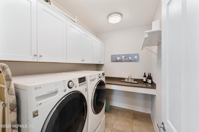 laundry area featuring washer and clothes dryer, cabinet space, baseboards, and light tile patterned floors