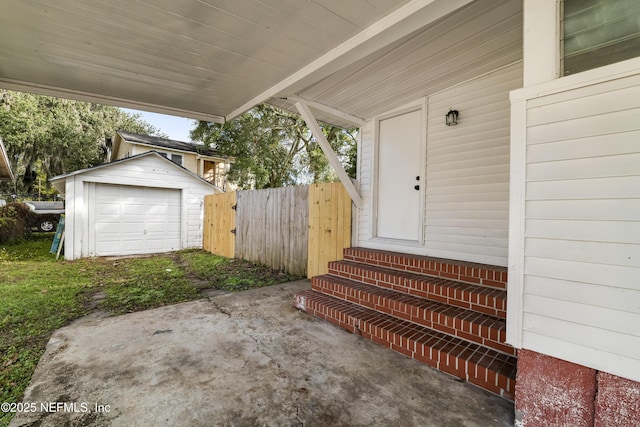 view of exterior entry featuring driveway and fence