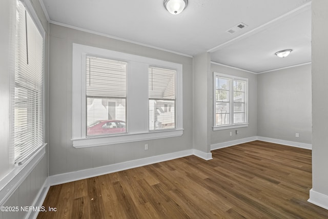 empty room with visible vents, crown molding, baseboards, and wood finished floors