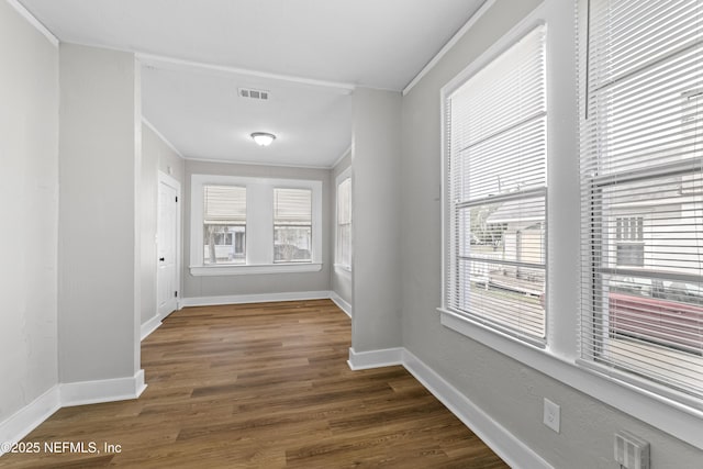 interior space with visible vents, dark wood-type flooring, baseboards, and ornamental molding