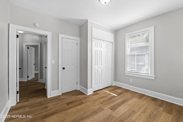 unfurnished bedroom with light wood finished floors, a closet, and baseboards