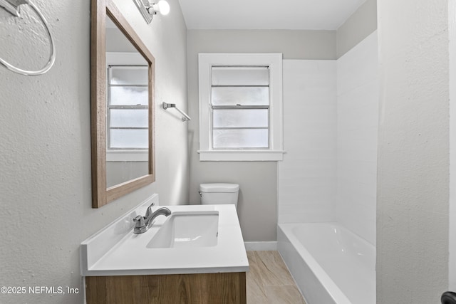 bathroom with toilet, vanity, and baseboards