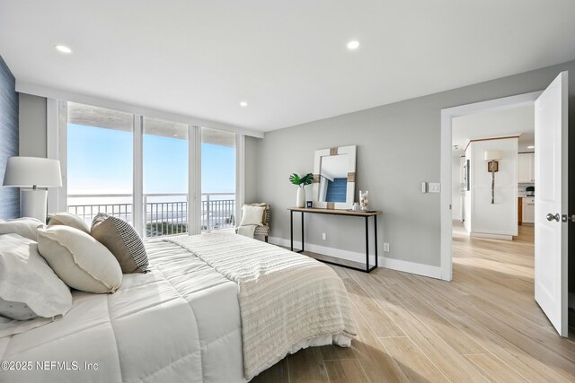 1601 Ocean Dr S Unit 410, Jacksonville Beach, FL 32250 - bedroom featuring access to exterior, a water view, recessed lighting, light wood-style floors, and expansive windows