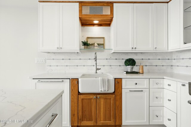 1601 Ocean Dr S Unit 410, Jacksonville Beach, FL 32250 - kitchen with a sink, decorative backsplash, white cabinetry, and light stone countertops