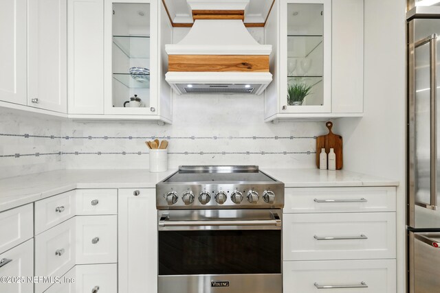 1601 Ocean Dr S Unit 410, Jacksonville Beach, FL 32250 - kitchen featuring high end appliances, custom exhaust hood, decorative backsplash, white cabinetry, and glass insert cabinets