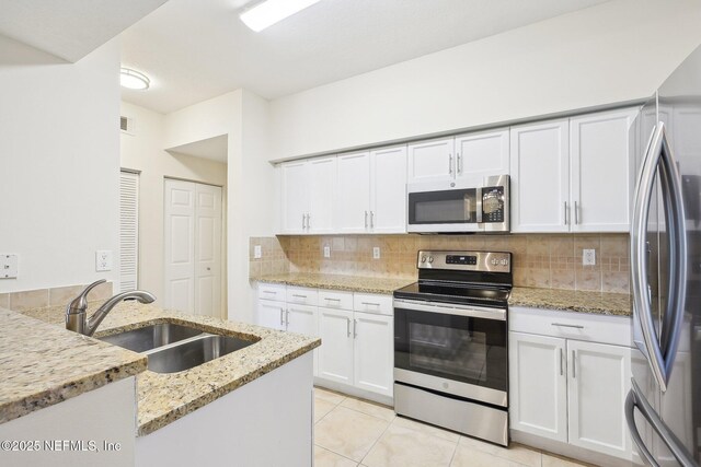 10435 Midtown Pkwy Unit 448, Jacksonville, FL 32246 - kitchen featuring white cabinets, a sink, stainless steel appliances, decorative backsplash, and light tile patterned flooring