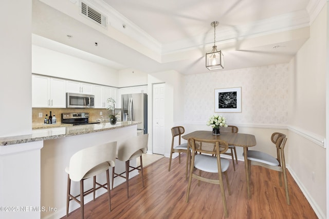 10435 Midtown Pkwy Unit 448, Jacksonville, FL 32246 - kitchen with a breakfast bar, light wood-style flooring, light stone countertops, visible vents, and stainless steel appliances