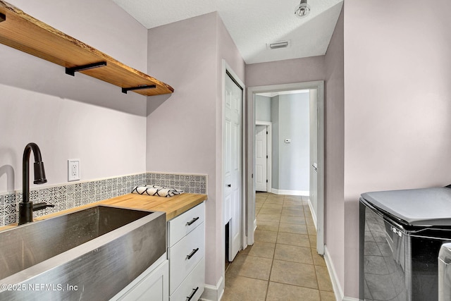 1317 Honeysuckle Dr, Saint Johns, FL 32259 - kitchen with visible vents, light tile patterned floors, a sink, white cabinetry, and wood counters
