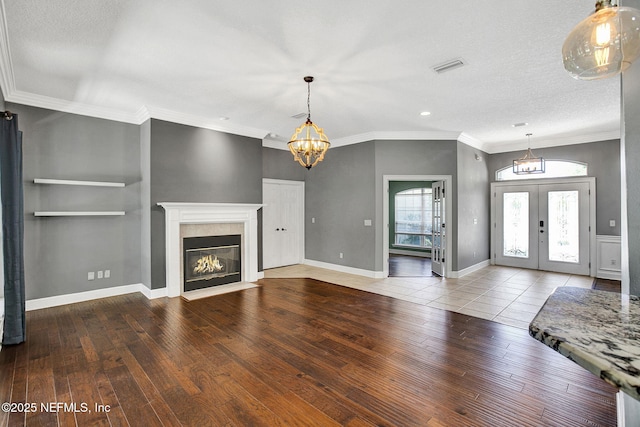 1317 Honeysuckle Dr, Saint Johns, FL 32259 - unfurnished living room featuring a chandelier, french doors, a fireplace with flush hearth, visible vents, and wood-type flooring