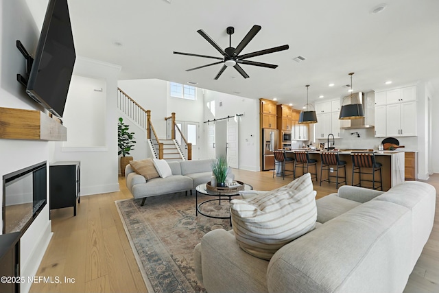 living area with a ceiling fan, visible vents, recessed lighting, a barn door, and light wood-type flooring