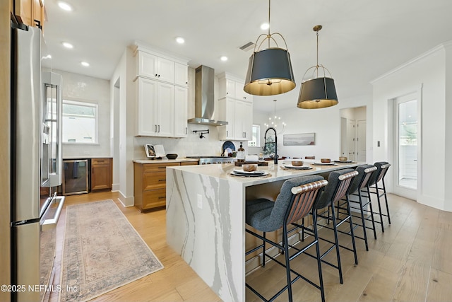 kitchen featuring light wood-style flooring, dishwasher, wall chimney exhaust hood, and stainless steel fridge with ice dispenser