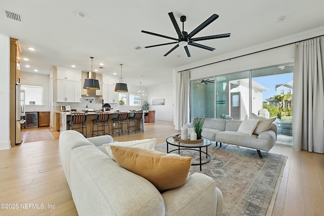 living room featuring a ceiling fan, baseboards, visible vents, recessed lighting, and light wood-type flooring