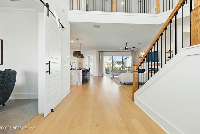 foyer entrance featuring stairway, visible vents, baseboards, light wood-style flooring, and a barn door