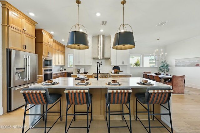 kitchen with a wealth of natural light, stainless steel appliances, visible vents, and wall chimney range hood
