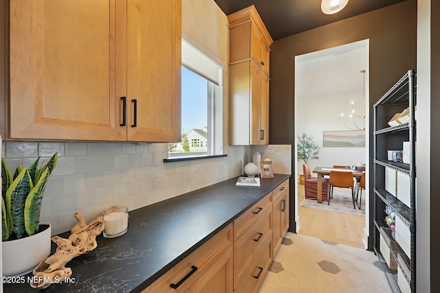 kitchen featuring decorative backsplash, dark countertops, and a chandelier