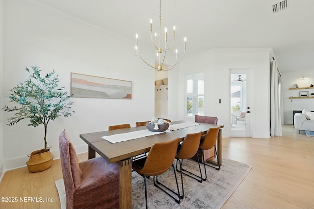 dining space featuring visible vents, an inviting chandelier, light wood-style flooring, and ornamental molding