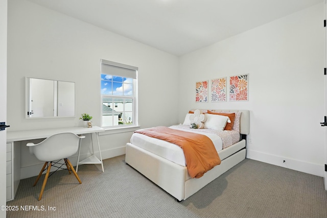 carpeted bedroom with baseboards and built in desk