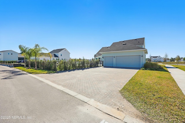 view of property exterior with fence, a residential view, decorative driveway, a yard, and a garage