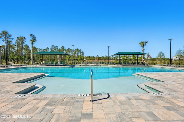 community pool with a patio area and fence