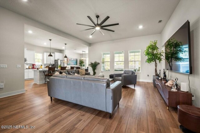 living room with wood finished floors, baseboards, and ceiling fan