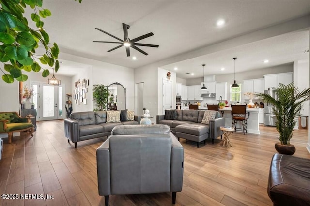 living area featuring a ceiling fan, light wood-style floors, and a healthy amount of sunlight