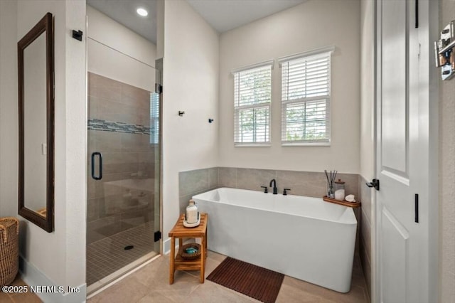 full bath with tile patterned floors, a soaking tub, and a shower stall