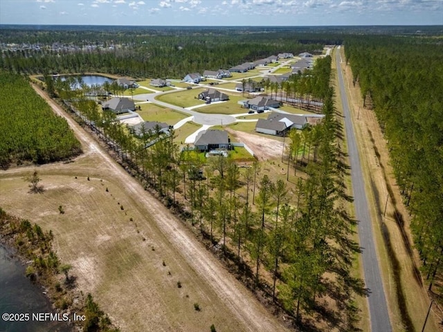 birds eye view of property with a wooded view and a water view