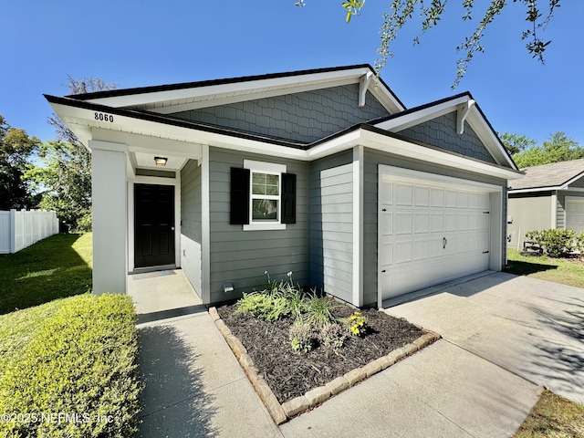 view of front of property with an attached garage, concrete driveway, a front lawn, and fence