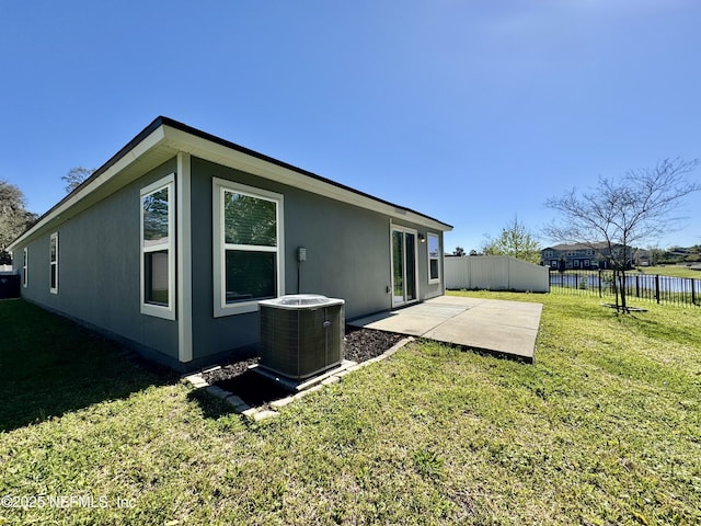 back of property with a patio area, fence, a lawn, and central AC