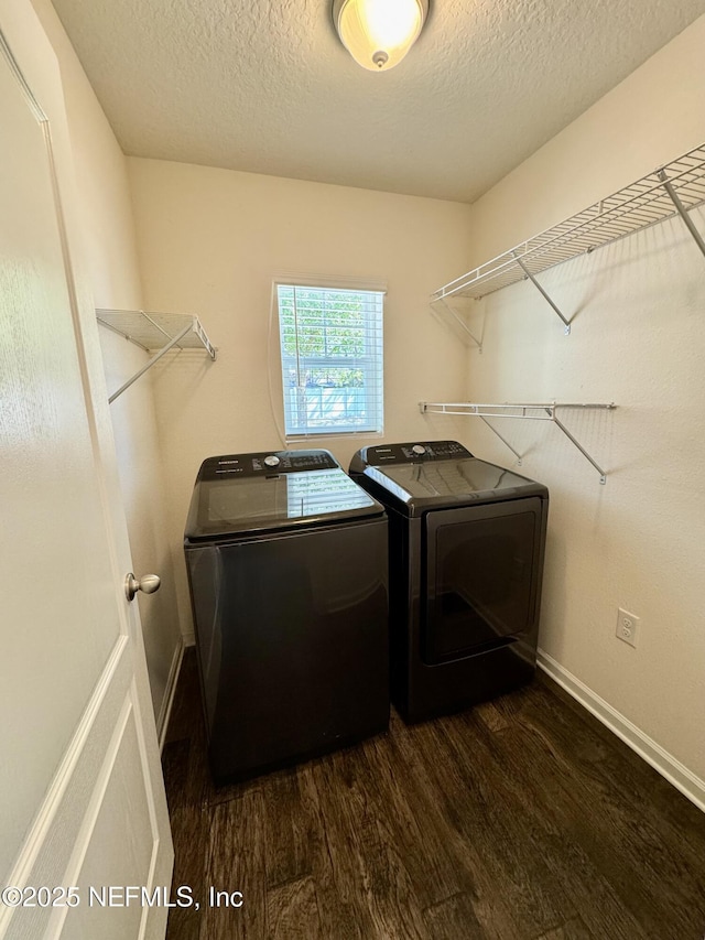laundry area with a textured ceiling, washing machine and dryer, laundry area, baseboards, and dark wood-style flooring