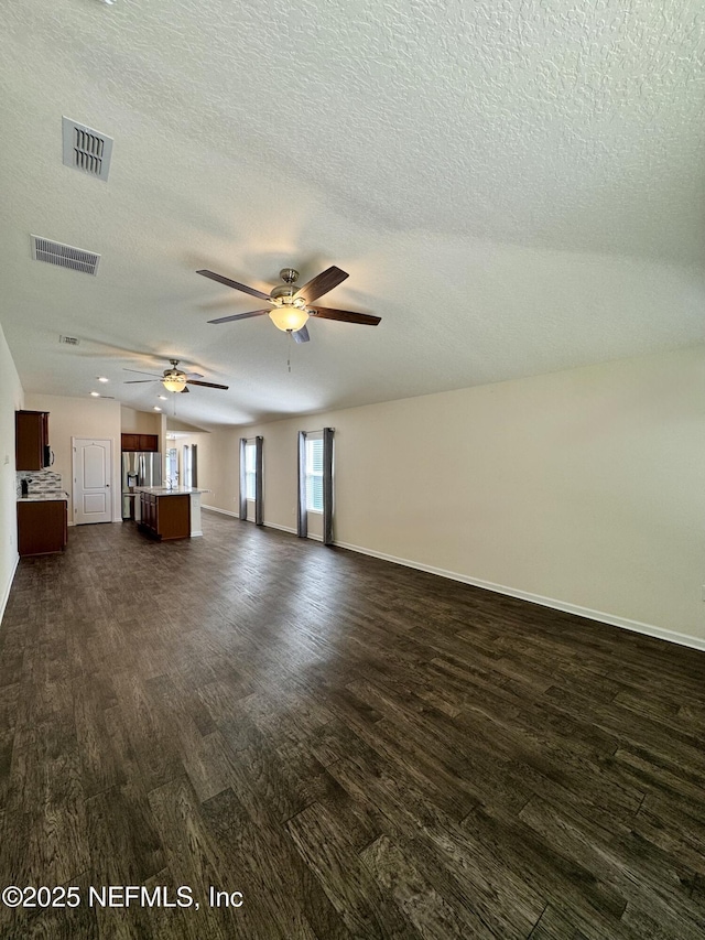 unfurnished living room featuring dark wood finished floors, baseboards, visible vents, and ceiling fan