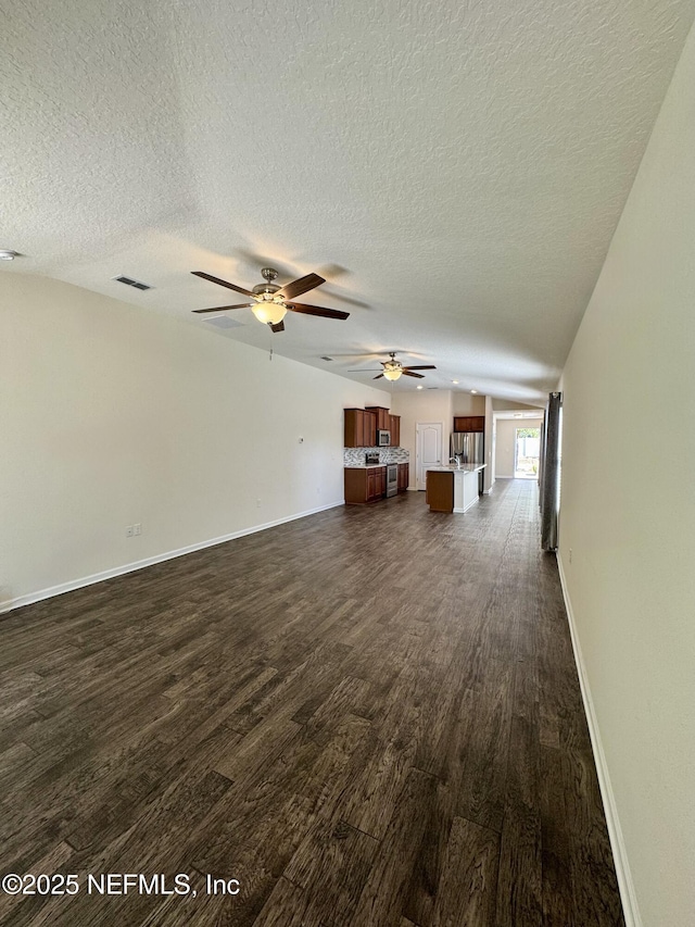 unfurnished living room featuring dark wood-style floors, baseboards, visible vents, ceiling fan, and a textured ceiling