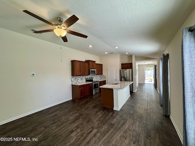 kitchen featuring lofted ceiling, a sink, decorative backsplash, dark wood-type flooring, and appliances with stainless steel finishes