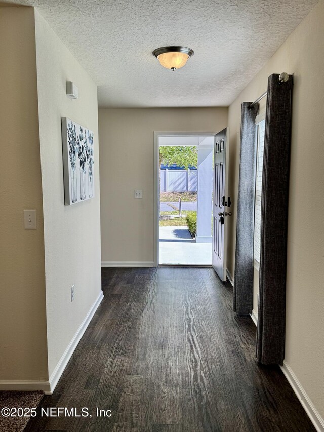 foyer with dark wood-style floors, baseboards, and a textured ceiling