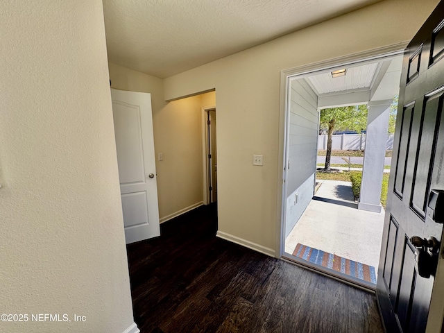 entrance foyer with baseboards, a textured ceiling, and wood finished floors