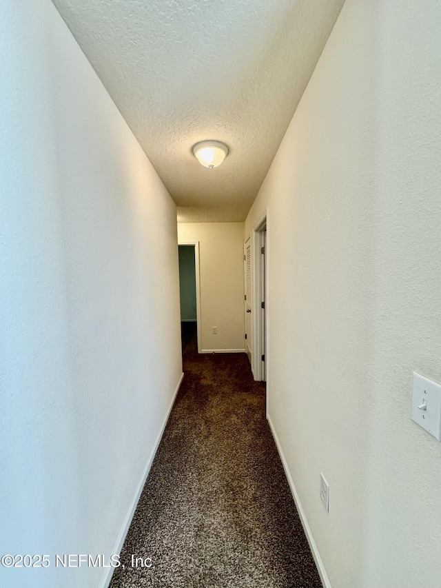 hall with baseboards, carpet, and a textured ceiling