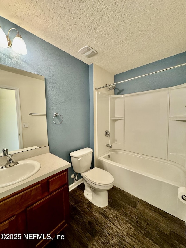 bathroom featuring toilet, a textured ceiling, wood finished floors, tub / shower combination, and vanity