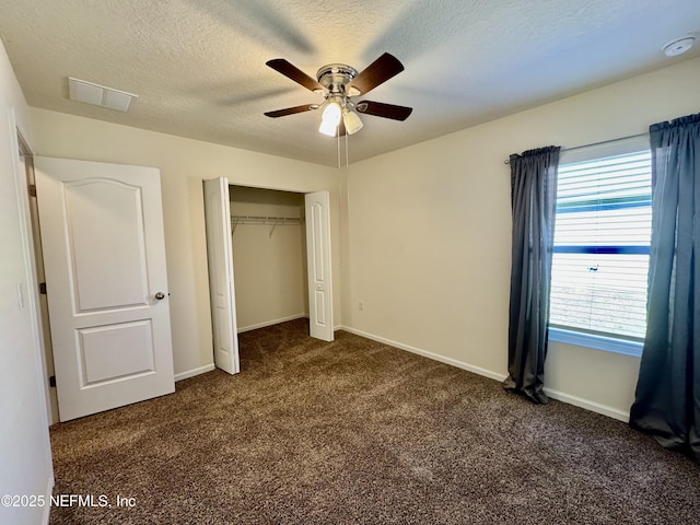 unfurnished bedroom with visible vents, a textured ceiling, a closet, carpet flooring, and baseboards