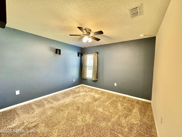 carpeted spare room featuring visible vents, a textured ceiling, baseboards, and a ceiling fan