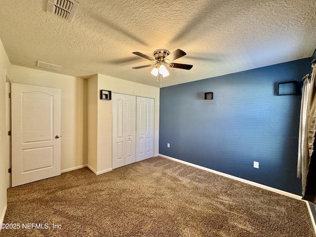 unfurnished bedroom featuring baseboards, visible vents, ceiling fan, a closet, and carpet flooring