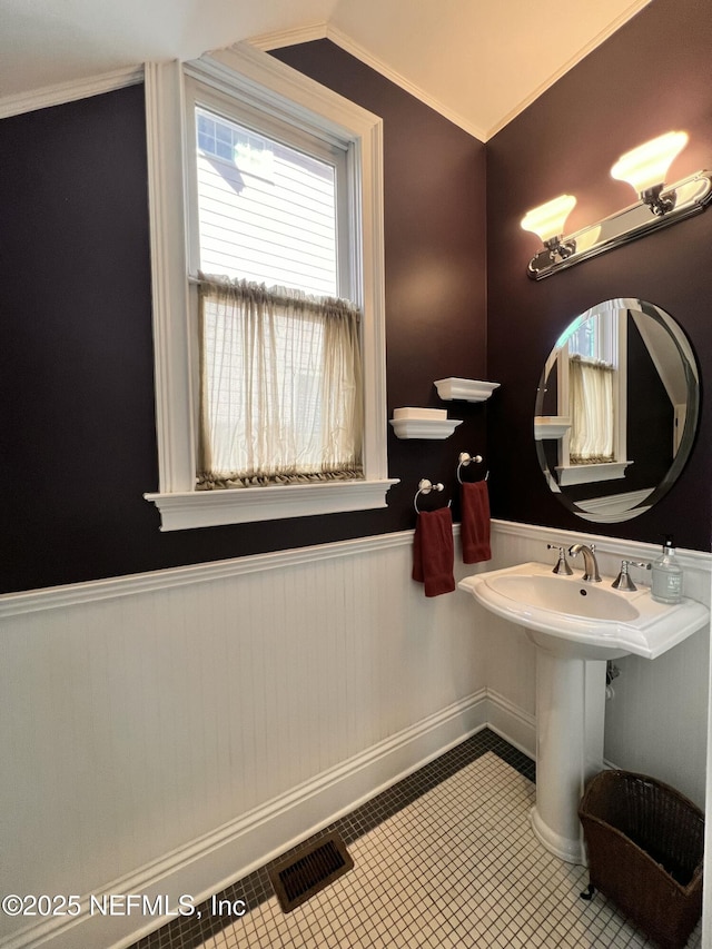 bathroom with visible vents, a wainscoted wall, ornamental molding, tile patterned flooring, and vaulted ceiling