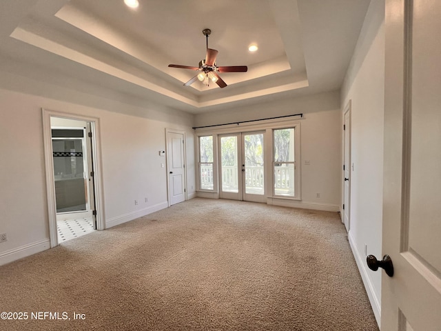 interior space featuring baseboards, access to exterior, light carpet, a raised ceiling, and connected bathroom