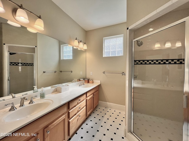 full bath featuring a sink, baseboards, double vanity, and a shower stall