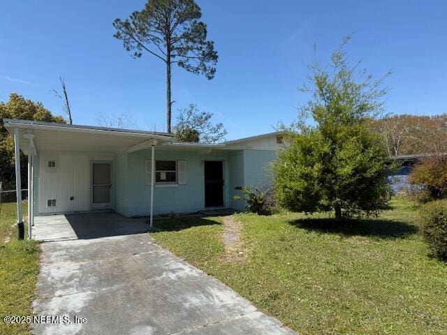 9504 Flechette Ave, Jacksonville, FL 32208 - view of front of house with a carport, concrete driveway, and a front lawn