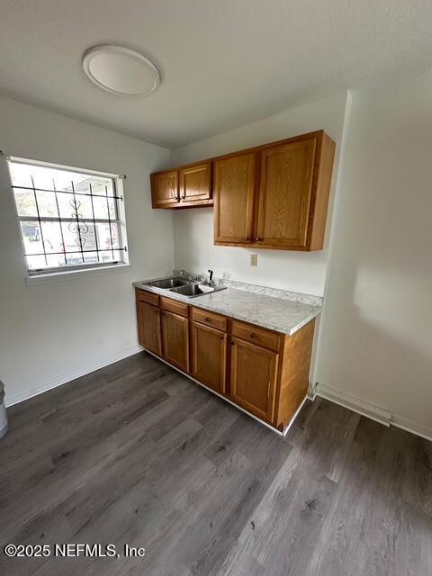 9504 Flechette Ave, Jacksonville, FL 32208 - kitchen with dark wood-style flooring, brown cabinets, light countertops, and a sink