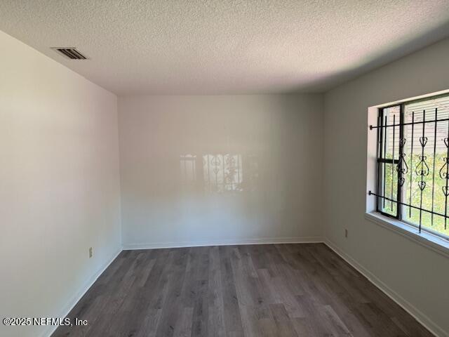 9504 Flechette Ave, Jacksonville, FL 32208 - spare room with a textured ceiling, baseboards, and dark wood-style flooring